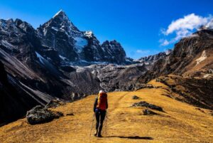 Hiker drinking from hydration bladder tube while walking on mountain trail