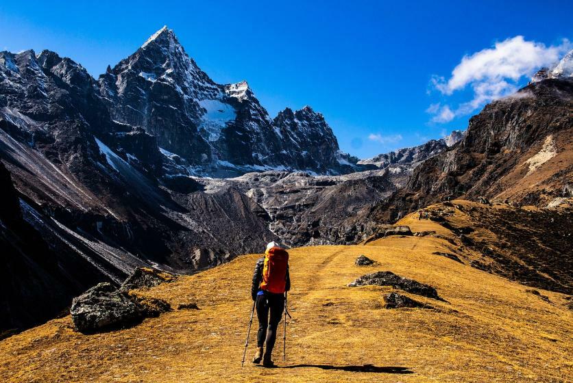 Hiker drinking from hydration bladder tube while walking on mountain trail